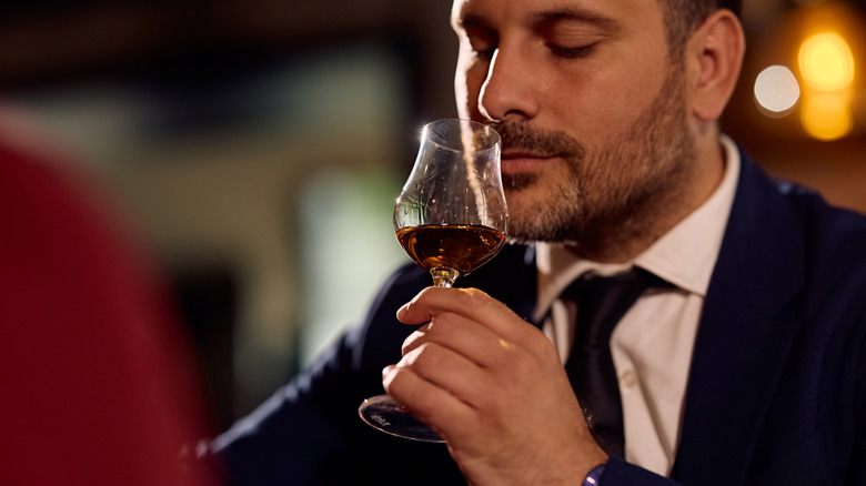 Man sniffing glass of whiskey