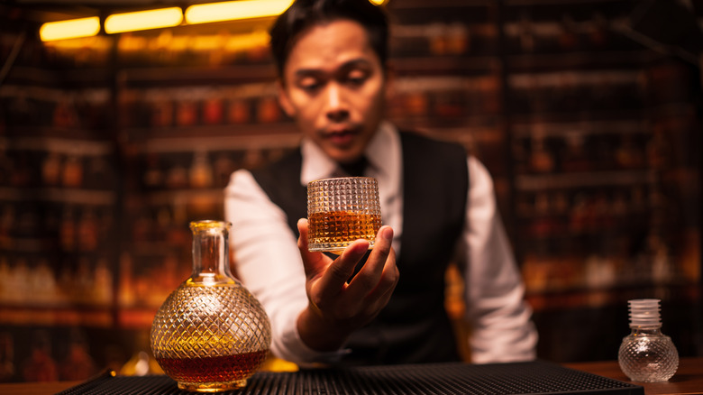 Bartender holding fancy glass of whiskey