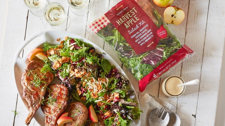 Harvest apple salad kit with dressing, fresh apples, and lamb chops with salad dressed on serving platter