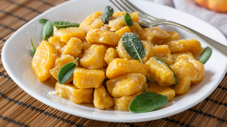 Pumpkin gnocchi with sage leaves on a white plate