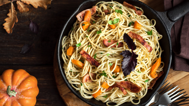 Pasta with pumpkin and bacon in cast iron pan