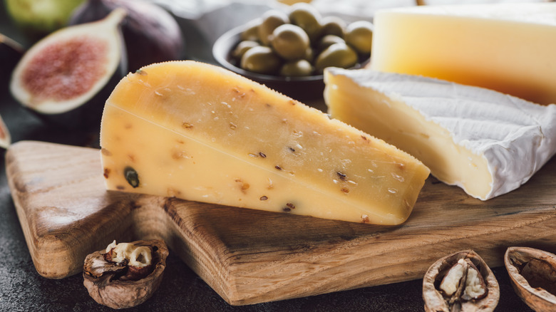 Cheeses on a board with nuts and figs