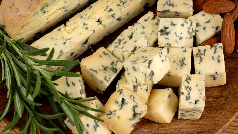 Blue cheese cut into chunks next to fresh rosemary