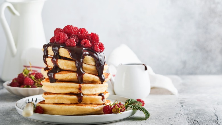 stack of pancakes with chocolate sauce and raspberries