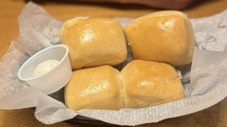 Four Texas Roadhouse rolls in a basket with cinnamon honey butter