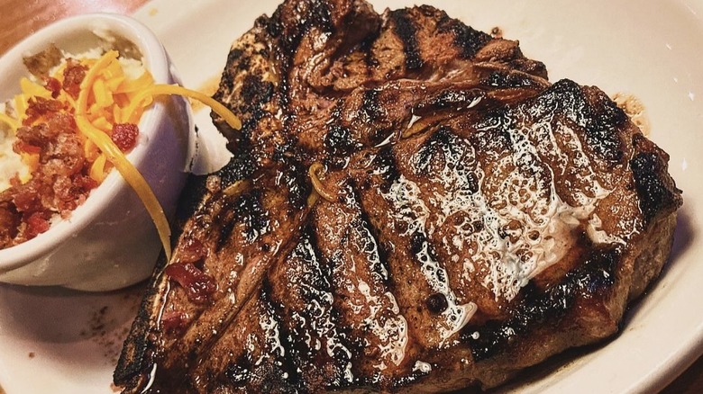 Juicy Texas Roadhouse steak on a white plate with loaded mashed potatoes on the side