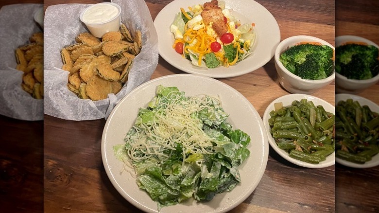 Texas Roadhouse fried pickles, house salad, and Caesar salad on a table