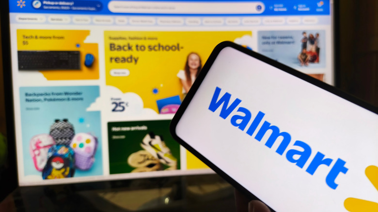 Walmart logo on phone in front of laptop on Walmart website