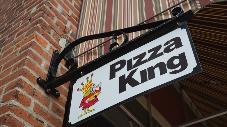 Pizza King sign on an outdoor brick building wall.