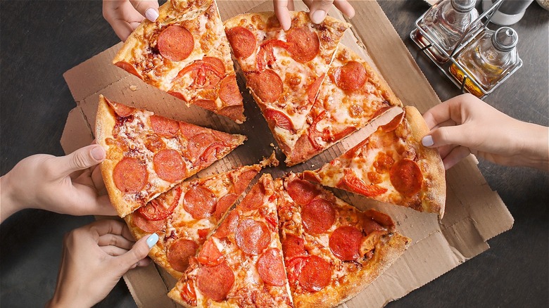 Pepperoni pizza being shared by friends