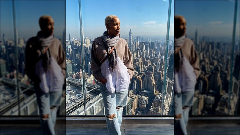 Elle Simone Scott posing in front of window overlooking the skyline
