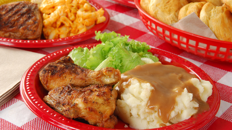 fried chicken and mashed potatoes on plate with macaroni and cheese plate in background