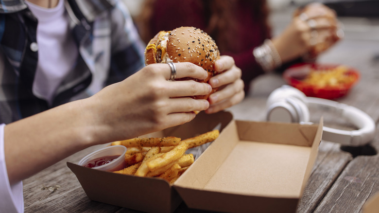 diners holding fast food burgers