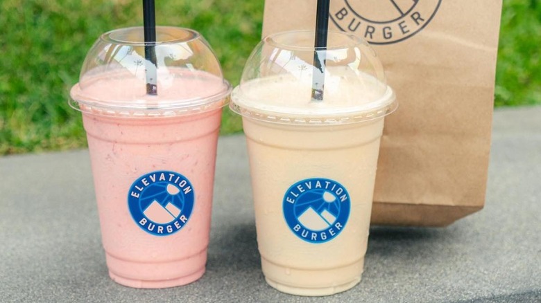 two Elevation Burger milkshakes with fast food bag in background