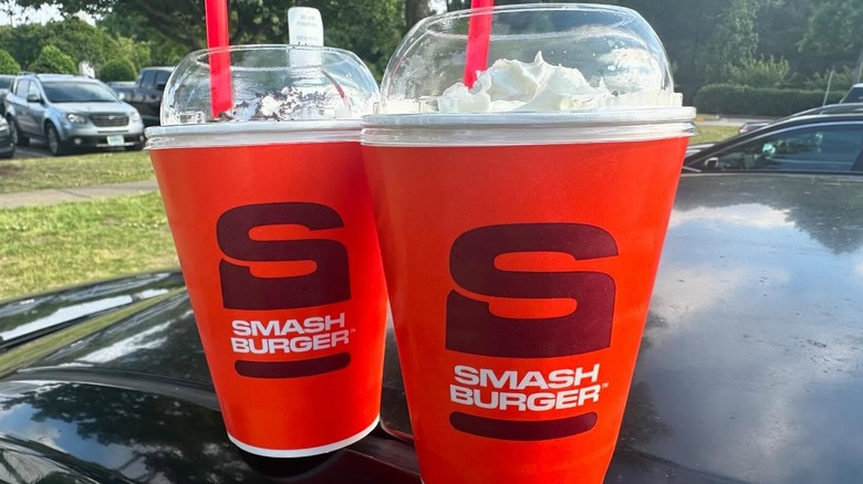 two Smashburger milkshakes in to-go cups with whipped cream on top