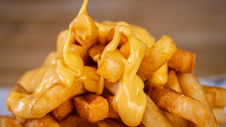 Cheese sauce being poured onto French fries
