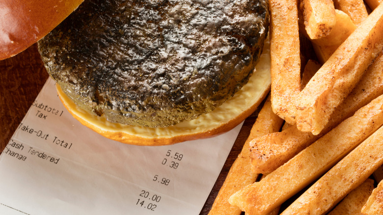 Close-up of burger and seasoned fries on top of a receipt totaling $5.98.