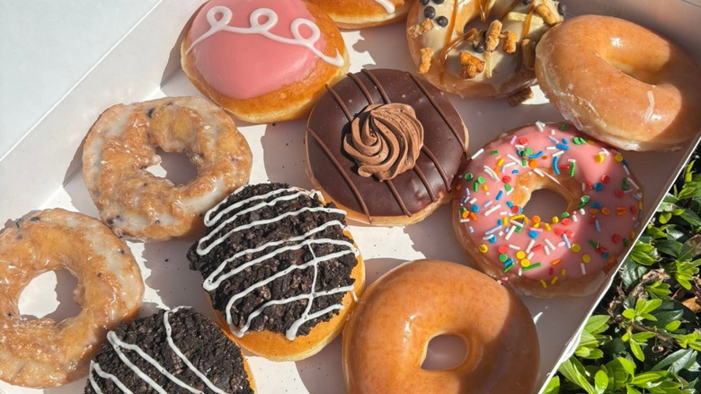 Close up of box of assorted, colorful doughnuts.