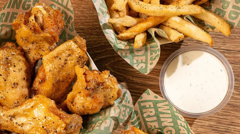 Close-up of Wingstop wings and seasoned fries, with side of ranch dressing.