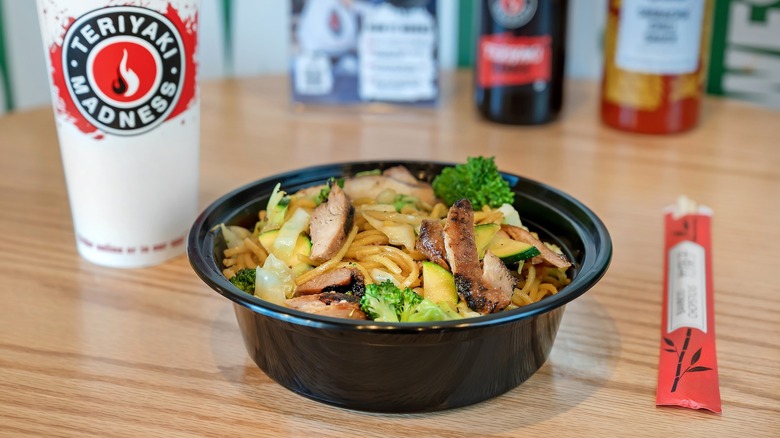 Teriyaki Madness noodle bowl with chopsticks and a drink