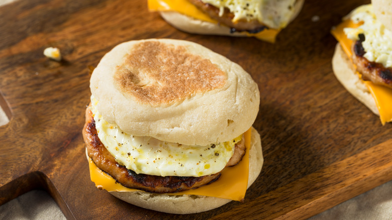 Breakfast sandwiches on English muffins on a wooden cutting board