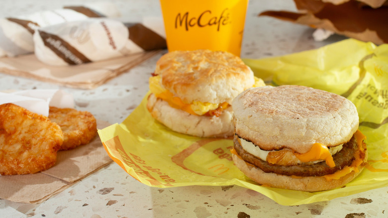 Two McDonald's egg mcmuffins and hashbrowns with a cup of coffee in the background