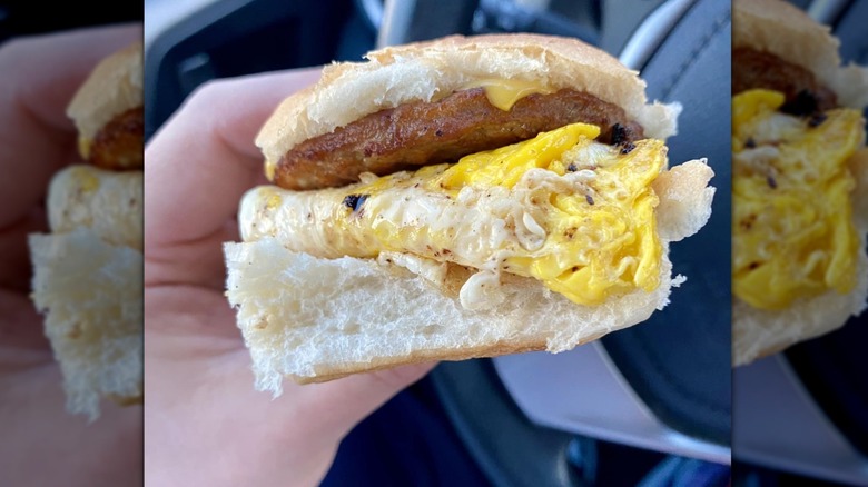 Hand holding a White Castle egg, sausage, and cheese sandwich