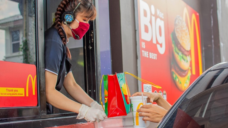 McDonald's employee handing food off in drive-thru