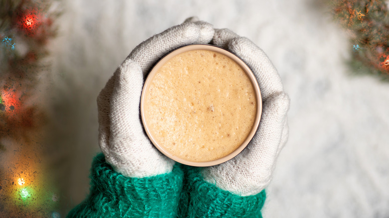 Person with mittens holding latte