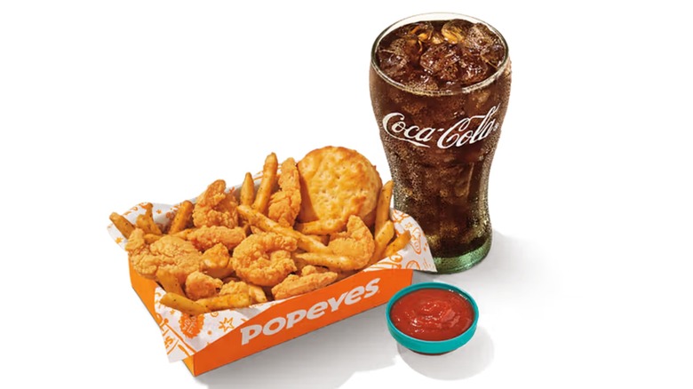 A basket of shrimp and fries with beverage and sauce from Popeyes.