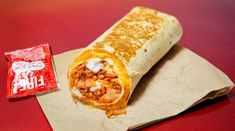 A Volcano Quesarito from Taco Bell next to a packet of Fire Sauce.
