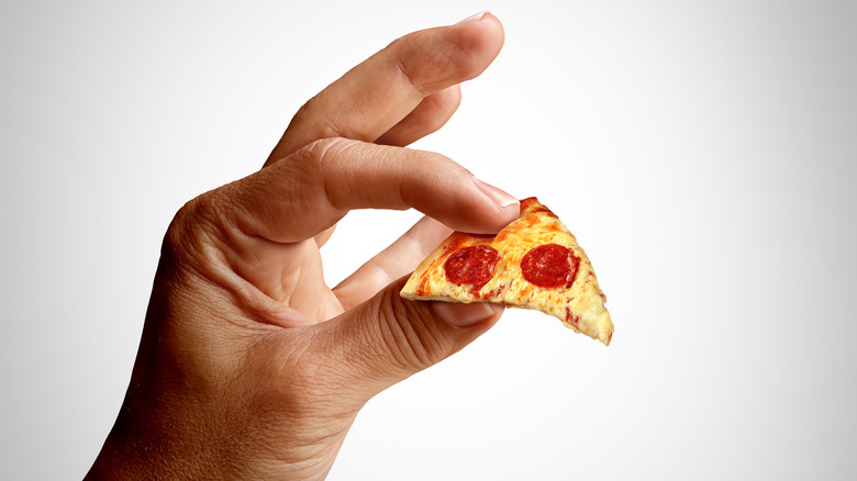 hand holding tiny slice of pizza
