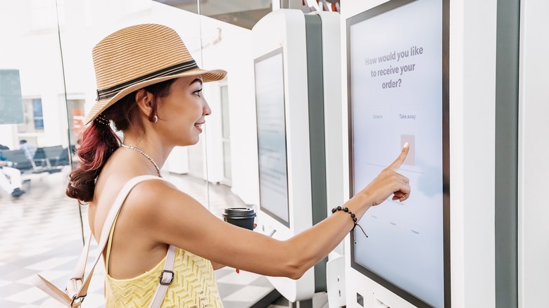 woman uses self-service kiosk