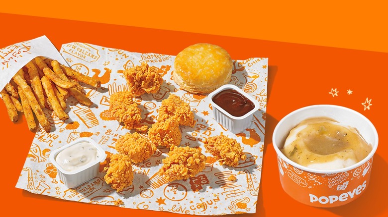 Popeyes' chicken meal with sauces, fries, biscuit, and mashed potatoes