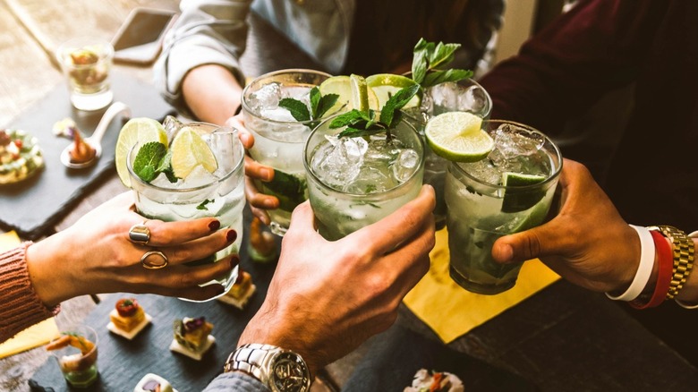 Hands clinking cocktail glasses together