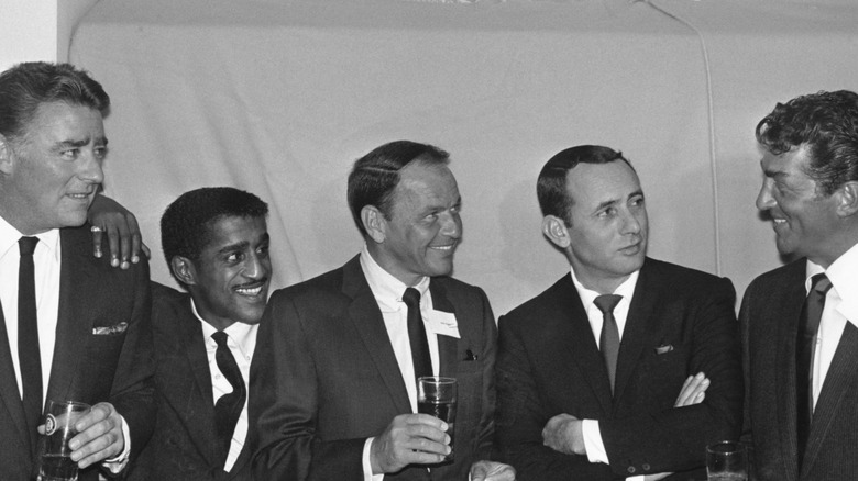 Rat Pack members Peter Lawford, Sammy Davis Jr., Frank Sinatra, Joey Bishop, and Dean Martin huddling.