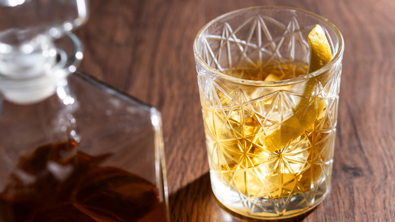 Rusty nail cocktail in a glass atop a wooden countertop.
