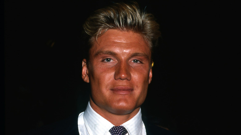 1980s action star Dolph Lundgren with a dark tan wearing a suit