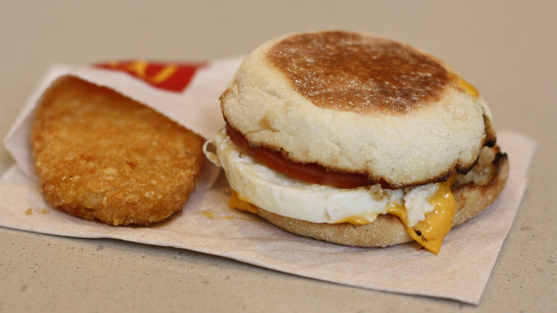 McDonald's egg McMuffin next to a hash brown in its paper envelope