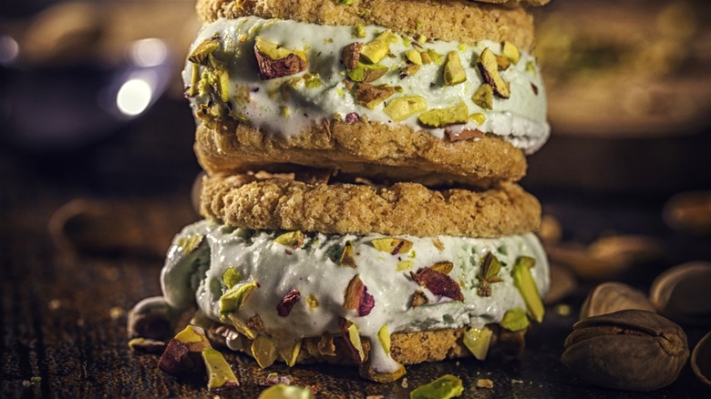 Oatmeal cookie ice cream sandwiches coated in chopped pistachios and stacked on top of each other.