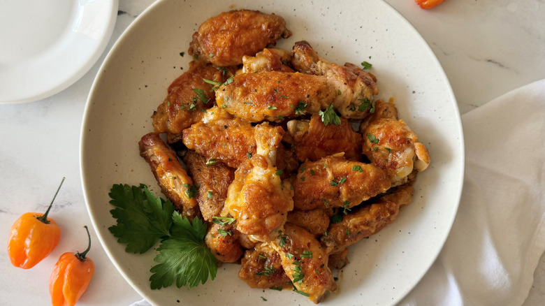 Mango habanero chicken wings in bowl garnished with chopped herbs