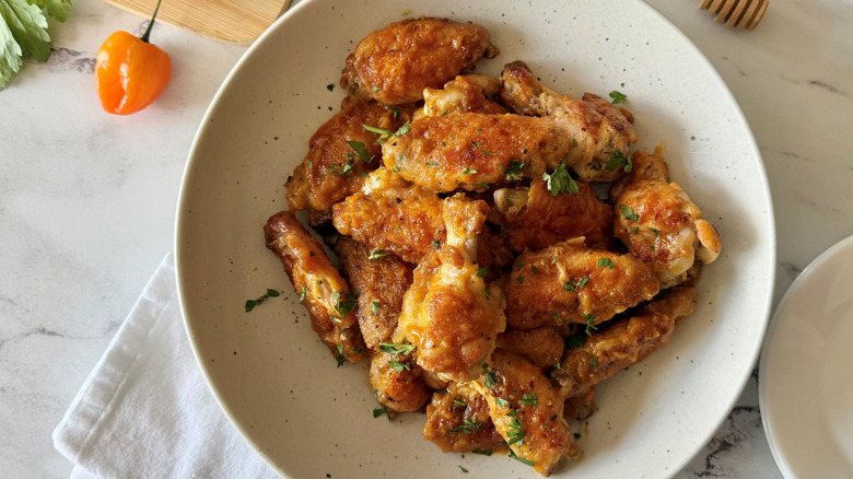 Mango habanero chicken wings in bowl garnished with chopped herbs