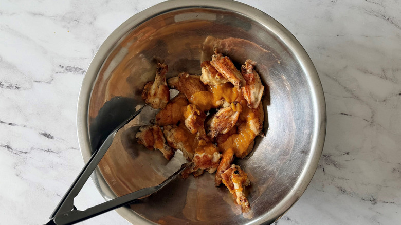 Tongs and mango habanero wings in bowl