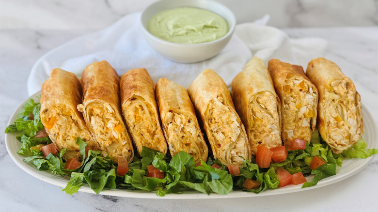 Chicken wraps served atop lettuce with bowl of avocado lime dip in background