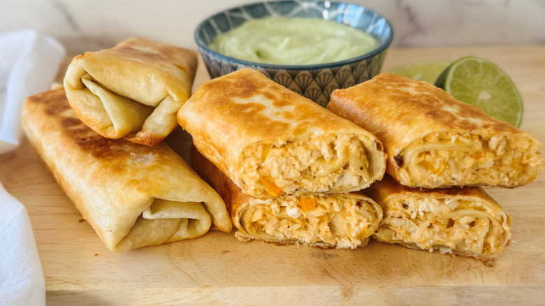 Chicken wraps with avocado dipping sauce on wooden board