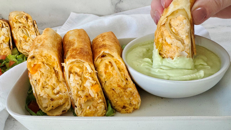 Chicken wraps on plate with one being dunked into avocado lime dip