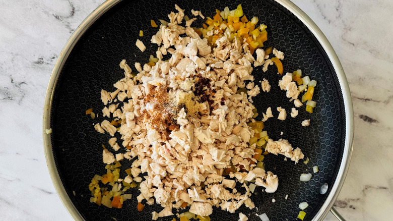 Diced chicken, veggies, and seasonings in pan