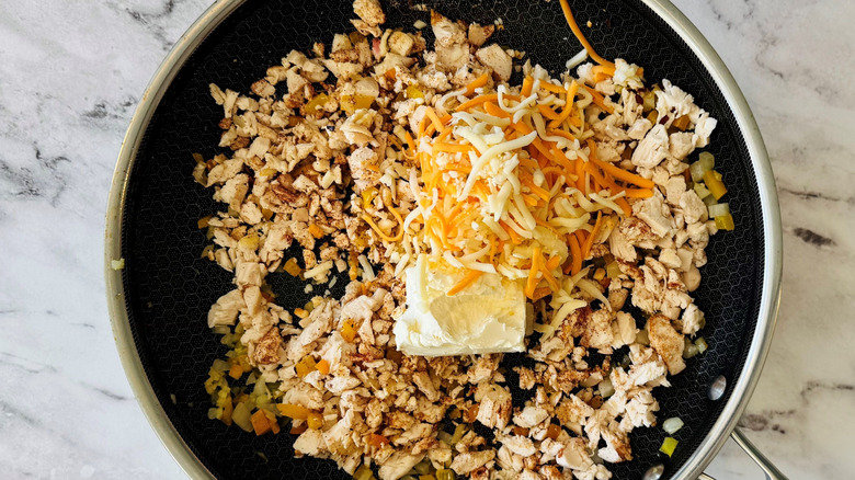 Diced chicken, cream cheese, and shredded cheese in pan