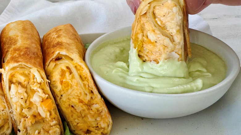 Chicken wrap dunking into avocado lime dip