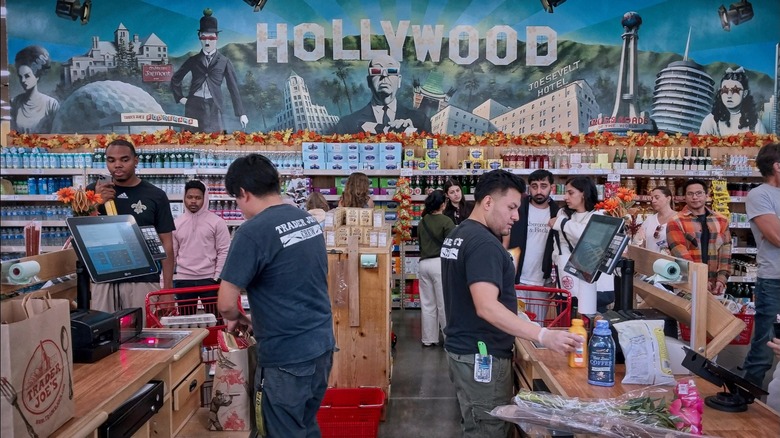 Customers and cashiers in Trader Joe's checkout area.